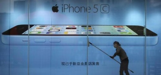 a worker cleaning in front of an iPhone 5C advertisement at an apple store in Kunming